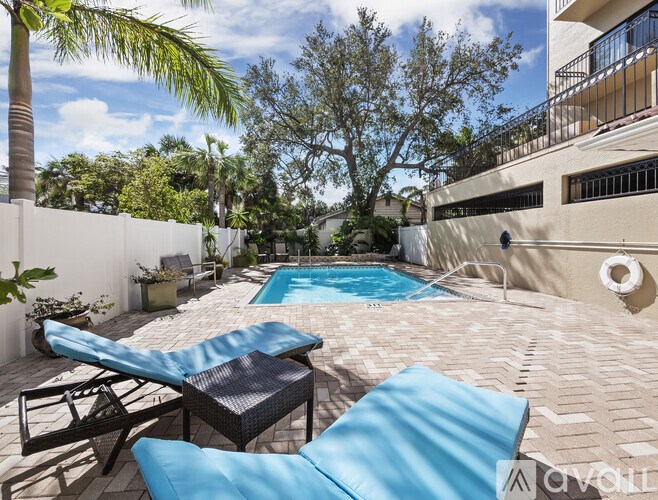 A patio with a pool and lounge chairs.