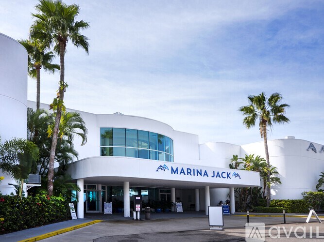 The Marina Jack building has a white exterior and is surrounded by palm trees.