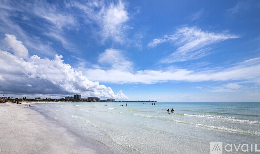 A beach scene with people in the water and buildings in the distance.