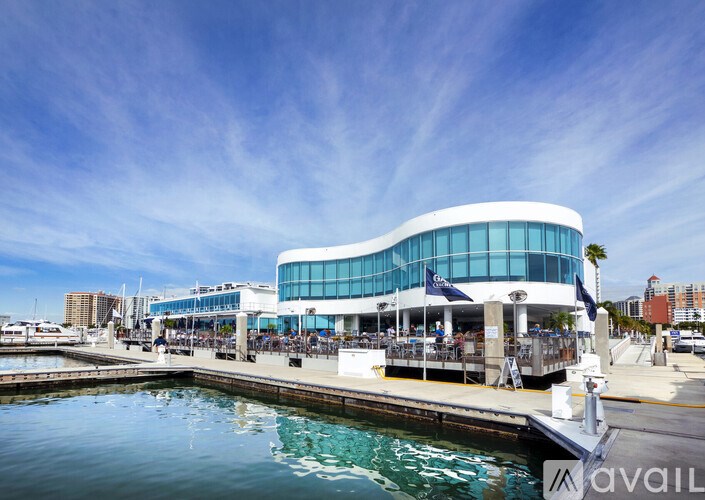 A modern building with a curved glass facade is situated by a body of water.