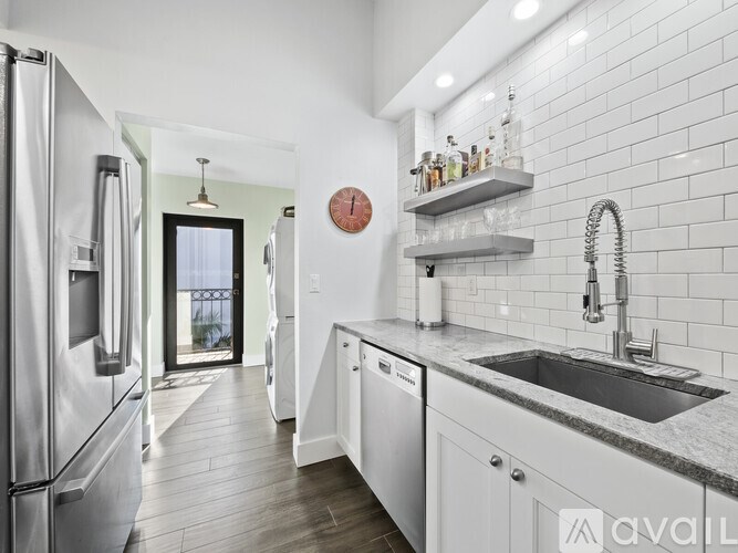 A kitchen with a refrigerator, sink, and a clock on the wall.