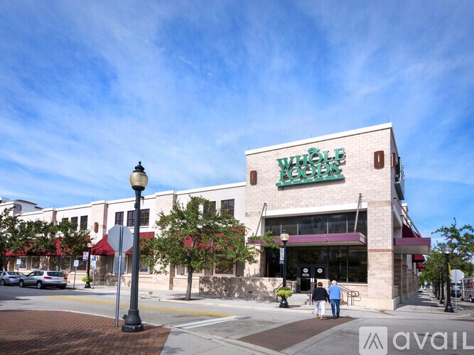 A Whole Foods store is located on a street corner with a pedestrian walking by.