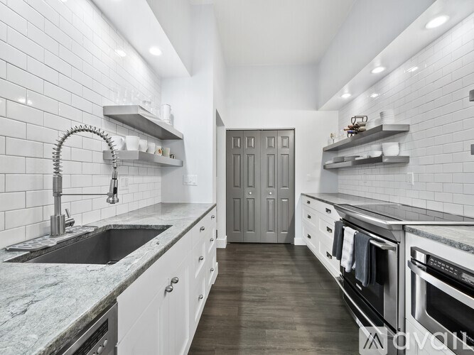 A modern kitchen with white cabinets and a marble countertop.