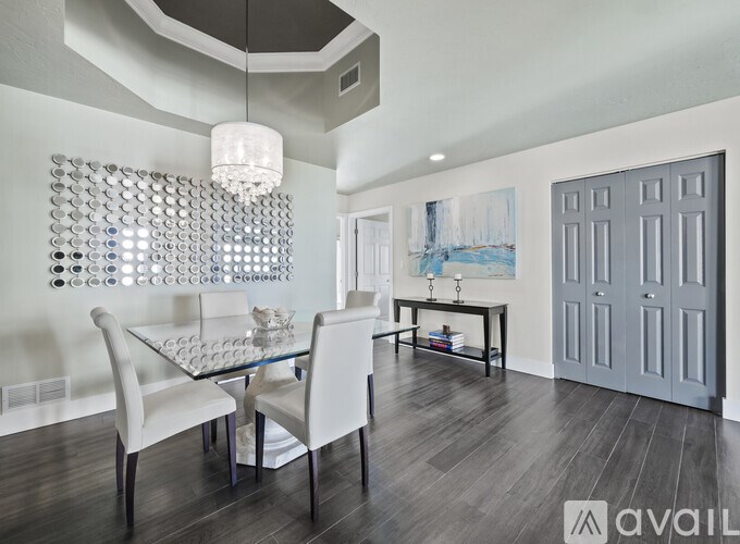 A modern dining room with a glass table and white chairs.