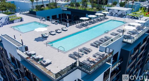 A rooftop pool area with lounge chairs and a building in the background.