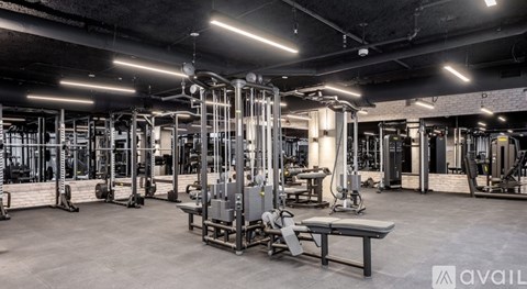 A gym with a variety of equipment including a squat rack, bench, and weights.
