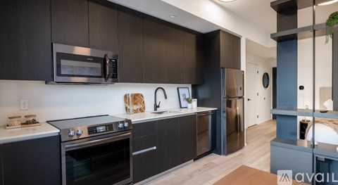 A modern kitchen with dark brown cabinets and stainless steel appliances.
