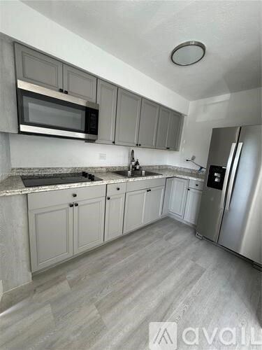 A kitchen with a refrigerator, microwave, and oven.