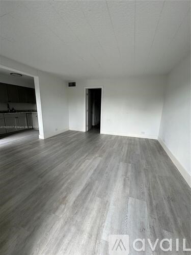 A room with wooden flooring and a door on the right side.