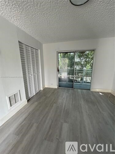 A room with a grey floor and a sliding glass door.