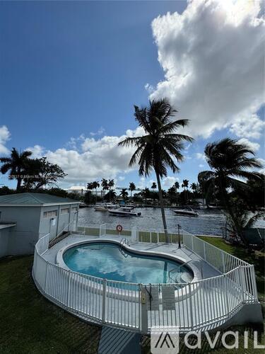 A pool surrounded by a white fence with palm trees in the background.