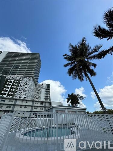 A tall building with a unique design stands next to a palm tree.