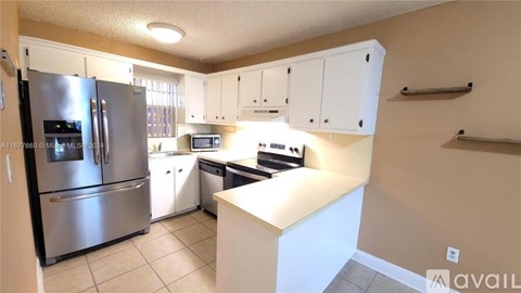 A kitchen with white cabinets and a stainless steel refrigerator.