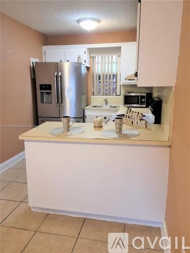A kitchen with a refrigerator, microwave, and sink.