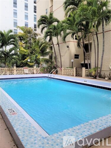 A swimming pool surrounded by palm trees and a building in the background.
