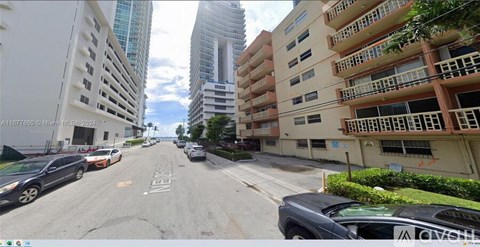 A street view of a city with cars parked on the side of the road.