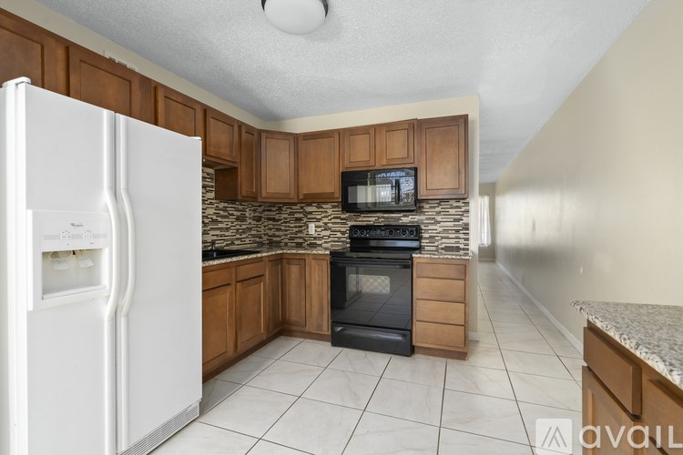 A kitchen with a white fridge, black oven, and wooden cabinets.