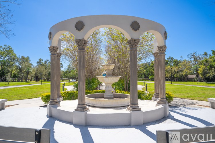 A white archway with columns and a fountain in the middle.