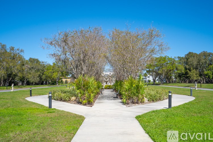 A park with a pathway, grass, and trees.