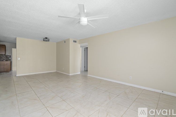 A spacious room with a fan on the ceiling and tiled flooring.