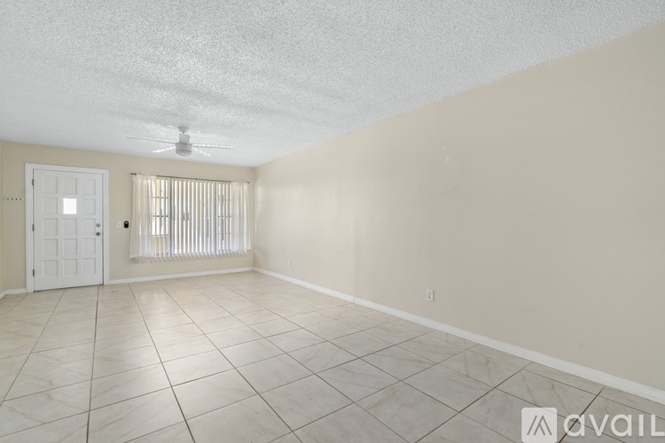 A room with a fan, tiled floor, and a door with blinds.