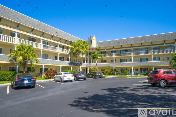 A parking lot in front of a hotel with cars parked.