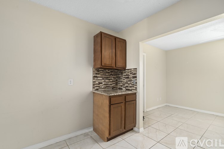 A kitchen area with a wooden cabinet and a stone backsplash.