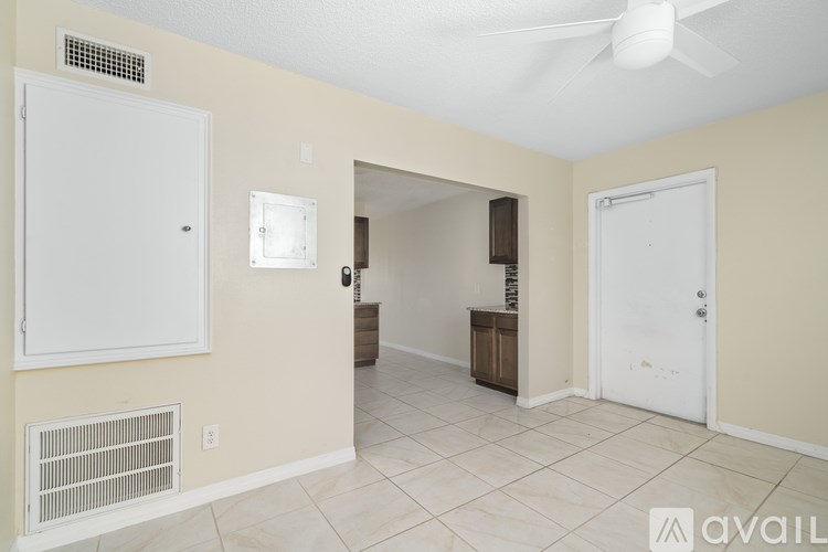 A room with a ceiling fan and a door on the right.