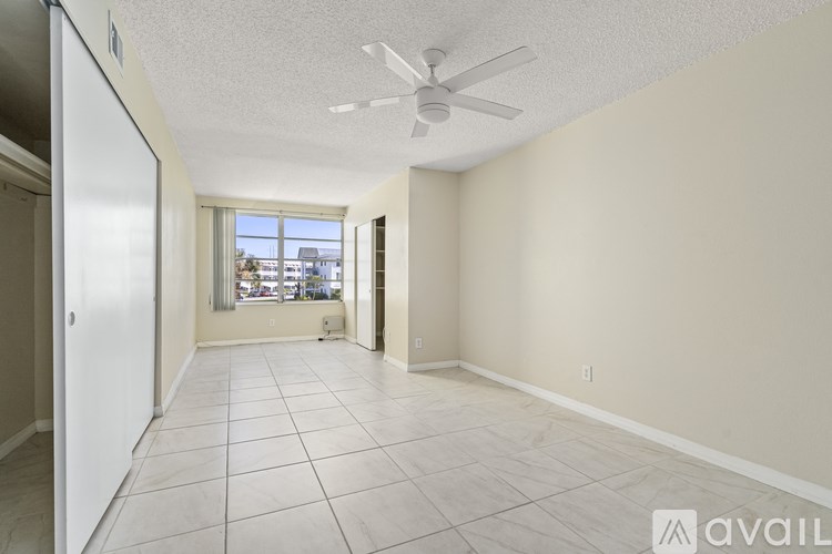 A spacious room with a ceiling fan and tiled flooring.