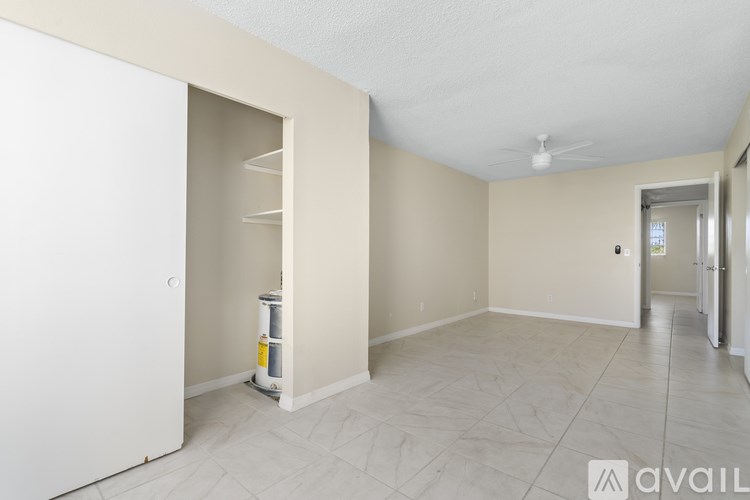 A spacious room with a white door and a tiled floor.