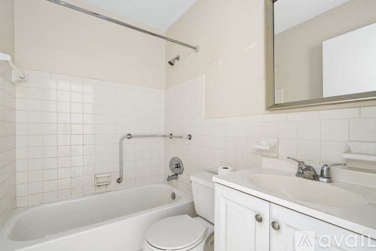 A white bathroom with a tub, toilet, sink and mirror.