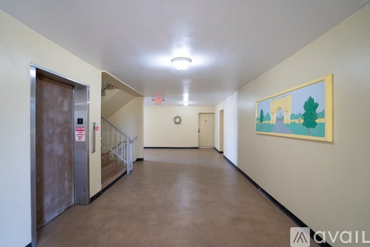 A hallway with a painting on the wall and a door on the left.