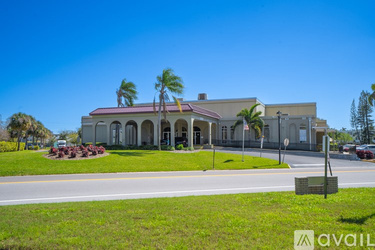 A building with a red roof and palm trees in front.