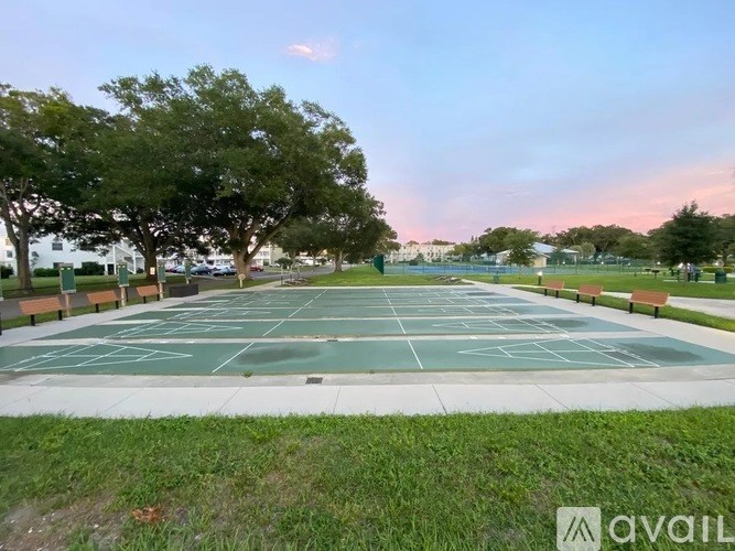 A tennis court surrounded by trees and benches.