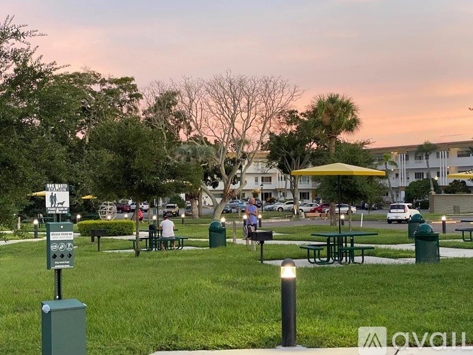 A park with picnic tables and people sitting at them.