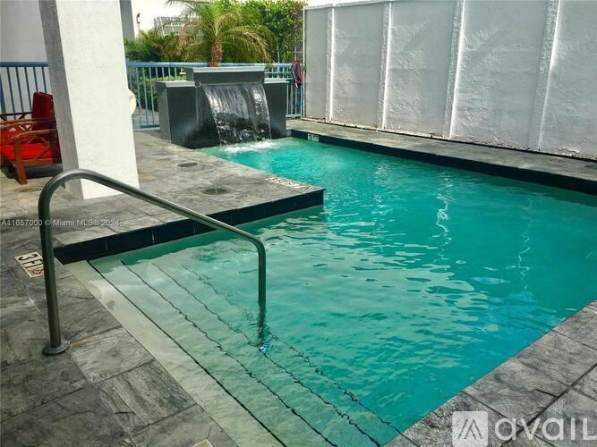 A pool with a waterfall and a red chair.