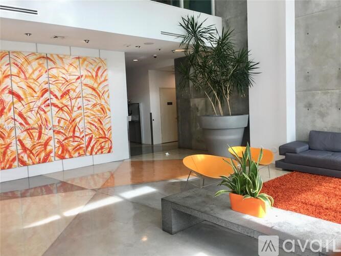 A living room with a grey couch, a coffee table, and a plant.
