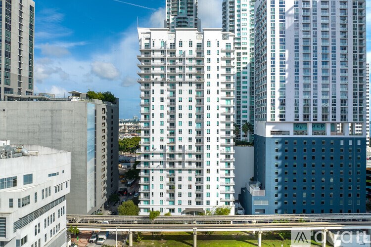 A cityscape with a mix of modern and older buildings, a clear sky, and a highway in the foreground.
