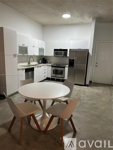A kitchen with a table and chairs in front of it.