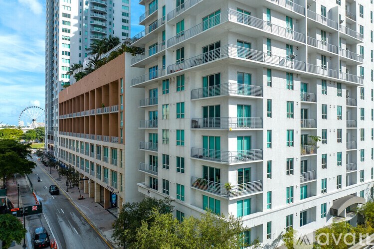 A tall white building with balconies overlooks a street.