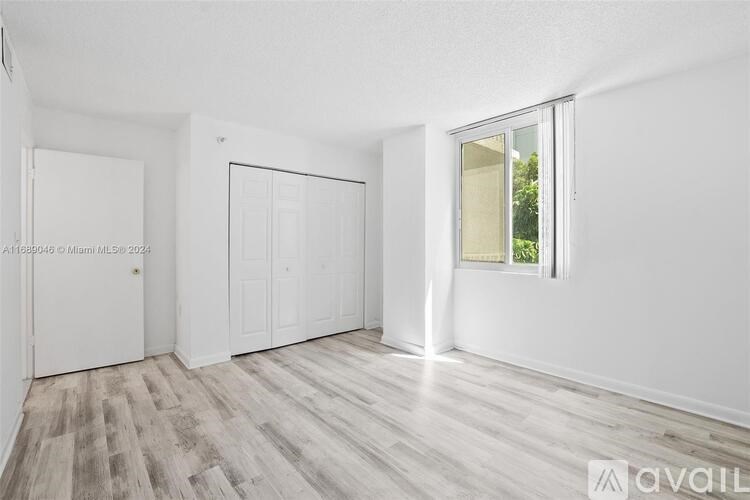 A room with white walls and wooden flooring, with a window on the right side.