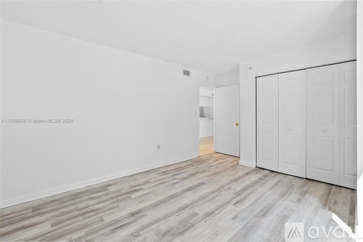 A spacious room with wooden flooring and white walls.