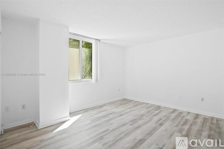 A spacious room with wooden flooring and a window.