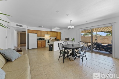 A living room with a tan couch and a dining table with chairs.