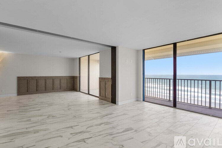 A spacious room with a view of the beach through the sliding glass doors.