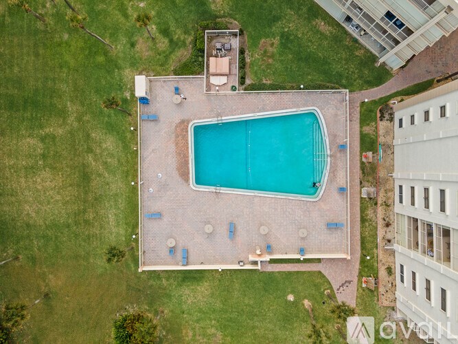 An aerial view of a swimming pool surrounded by a brick patio and a grassy area.