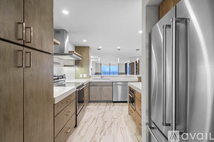 A modern kitchen with a stainless steel refrigerator and wooden cabinets.