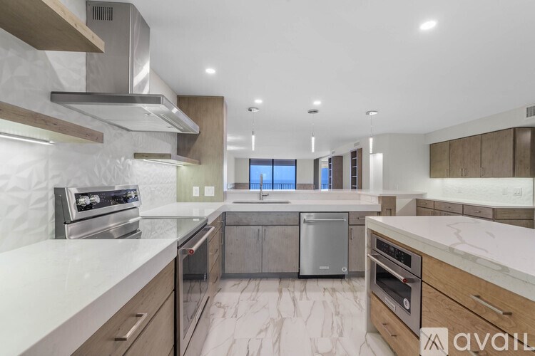 A modern kitchen with stainless steel appliances and marble countertops.