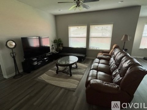 A living room with a brown leather couch and a glass coffee table.