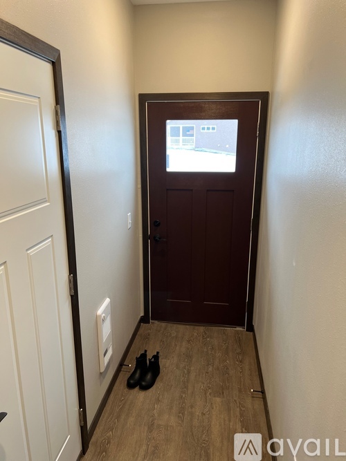 A pair of black shoes are on the floor of a hallway.